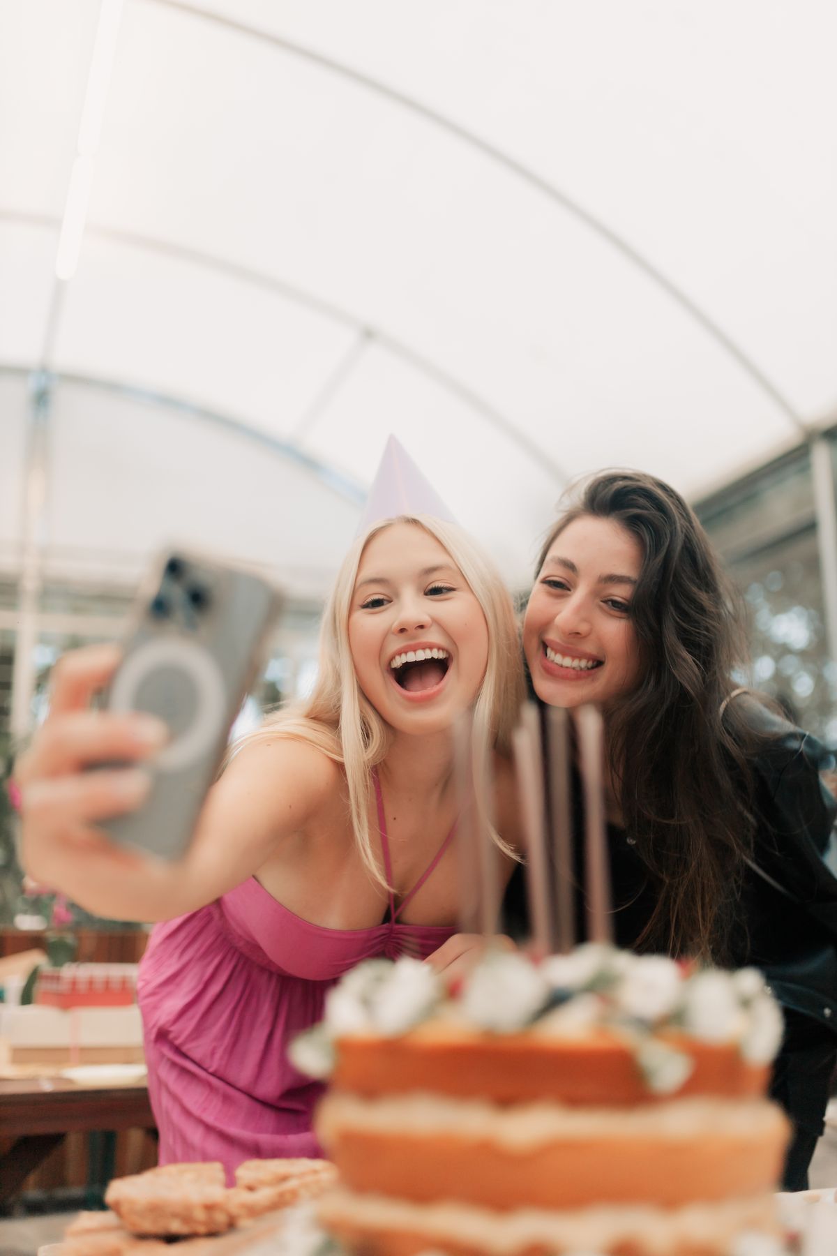 Friends celebrating a birthday with a cake and phone selfie