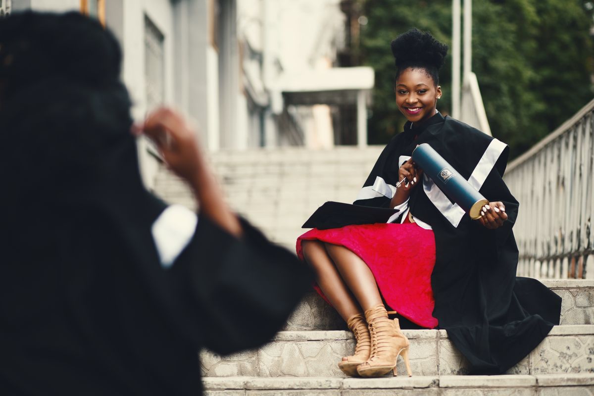 Graduate sitting outdoors in a cap and gown after commencement